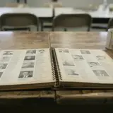 Worn, yellowed church directory lying open on a fellowship hall table under fluorescent lights