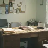 Empty church office desk with stacked folders and ledger book in soft afternoon light