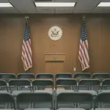 Empty congressional press conference room with podium and American flags under fluorescent lighting