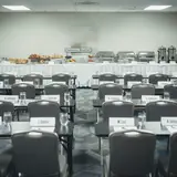 Empty hotel conference room with rows of chairs, name placards, and untouched continental breakfast spread