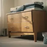 Slightly tilted wooden dresser in a suburban bedroom with a bag of unused screws on the floor beside it