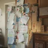 Kitchen refrigerator completely covered in overlapping children's colorful drawings and paintings