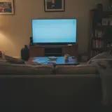 Glowing smart television in a dark suburban living room with an empty couch