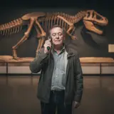Middle-aged man listening intently to audio guide alone in empty natural history museum gallery